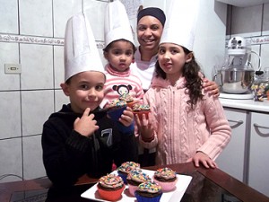 A chef Bete Carneiro ensina crianças a fazer cupcakes.